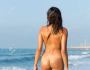 113461902, absolutely naked young woman standing back to viewer on sand beach near azure sea1